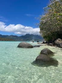 A picturesque view of a serene coastline with clear turquoise waters and rocky formations, perfect for showcasing the beauty of island destinations.