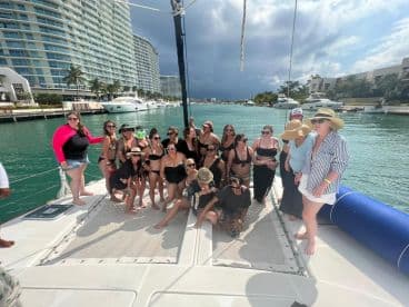 A lively group of friends enjoys a fun day on a catamaran, celebrating together in the sun — perfect for bachelorette parties or group outings on the water.