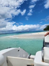 A stunning view from a boat approaching a picturesque beach with turquoise waters and white sand, perfect for island hopping adventures.