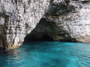 A stunning view of a coastal cave with crystal-clear turquoise waters, perfect for exploring the natural beauty of the area.
