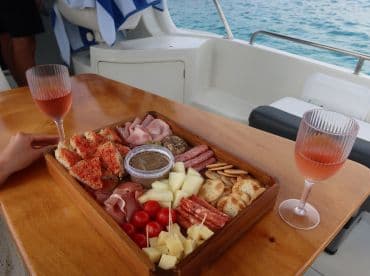 A beautifully arranged charcuterie board with assorted meats, cheeses, and cocktails, perfect for enjoying onboard a boat. Ideal for a relaxing day at sea.