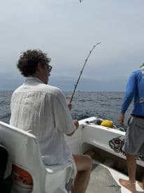 A man enjoys a fishing experience on a boat, casting his line into the ocean — a perfect moment for fishing enthusiasts seeking adventure on the water.