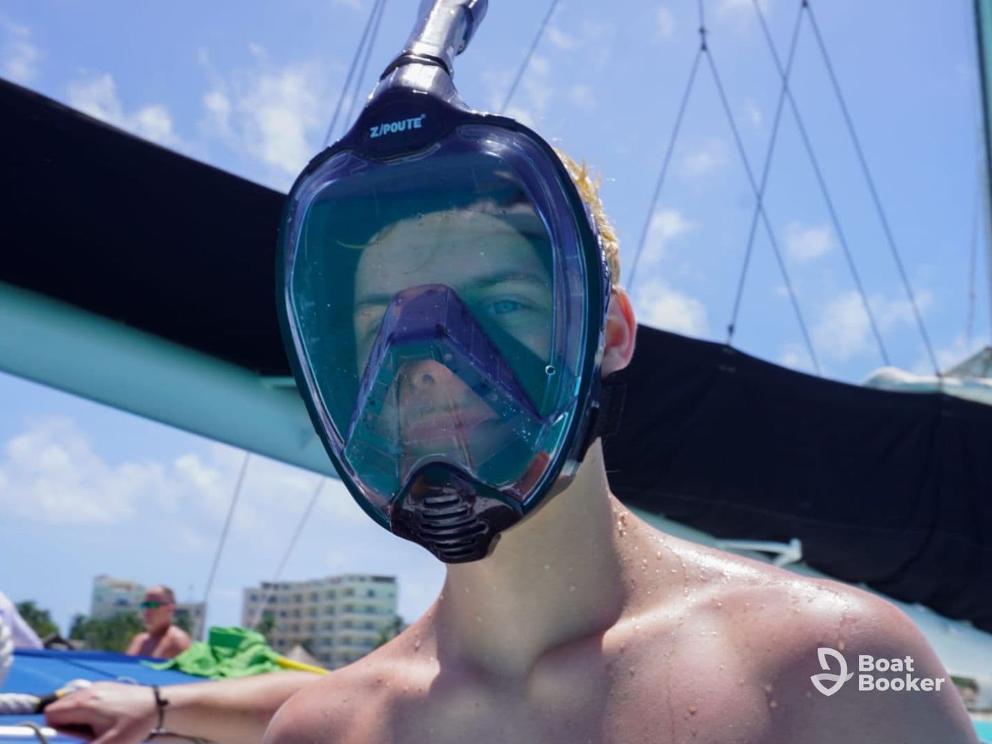 A young adult prepares for snorkeling with a full-face mask, showcasing the excitement of underwater exploration during a boating adventure.