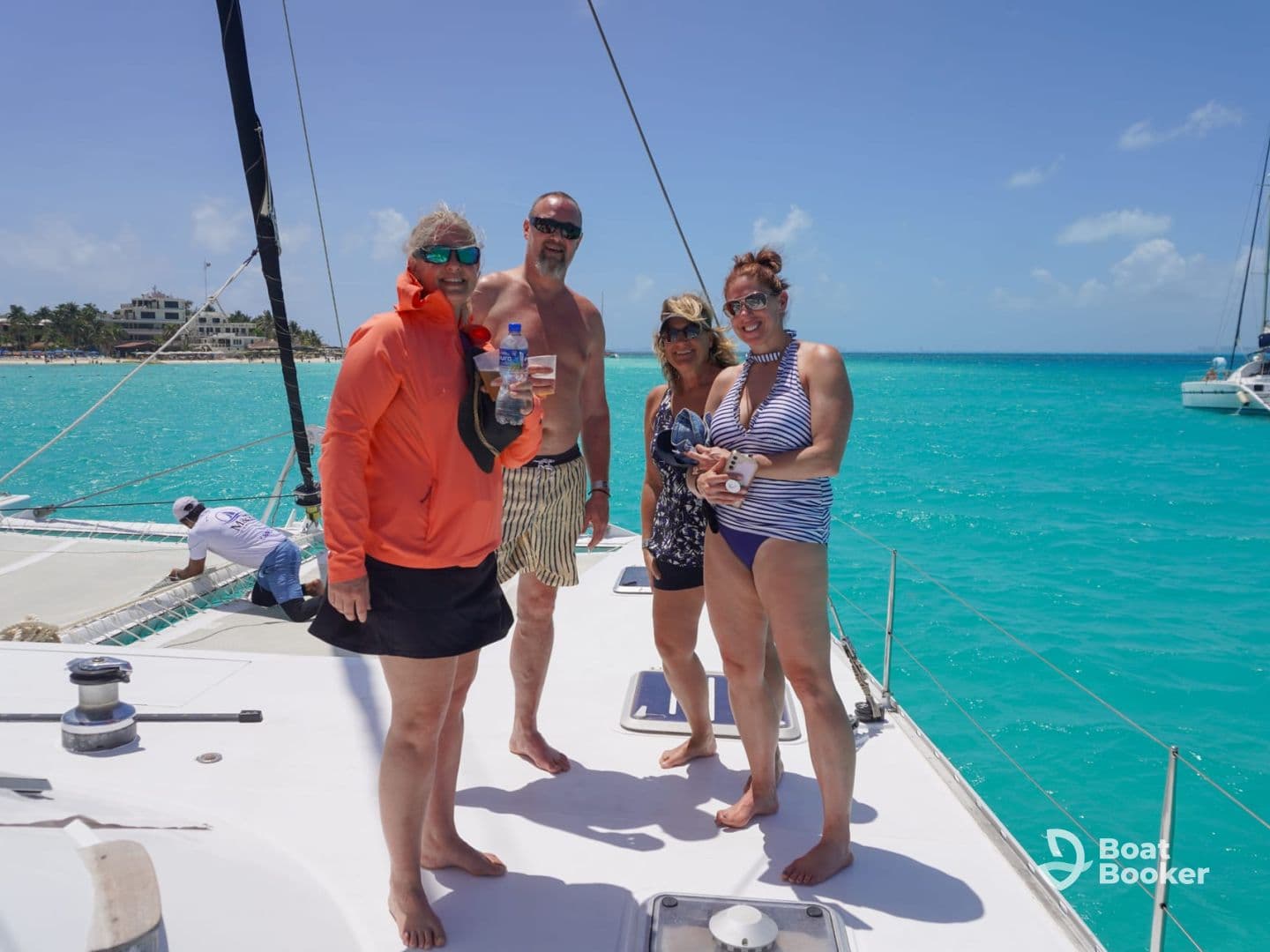 A cheerful group enjoys drinks aboard a catamaran, surrounded by stunning turquoise waters — perfect for a fun day on the ocean.