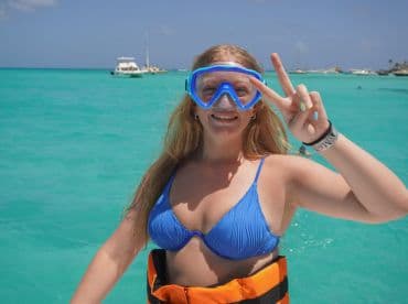 A young woman enjoys snorkeling in the vibrant turquoise waters, showcasing the fun and excitement of a beach adventure.