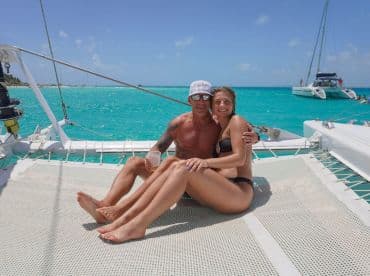 A happy couple enjoys a sunny day on a catamaran, surrounded by stunning turquoise waters — perfect for romantic getaways or beach celebrations.