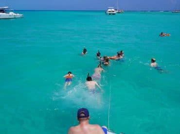 A lively group enjoys snorkeling in the crystal-clear turquoise waters, creating unforgettable memories on their aquatic adventure.