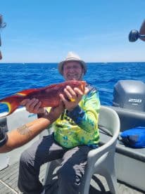 A joyful angler proudly displays his catch while fishing in the open ocean, showcasing the thrill of a successful day on the water.