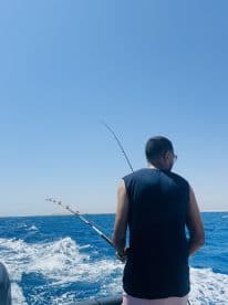 A man enjoys a fishing experience on the open water, showcasing the thrill of angling amidst beautiful ocean scenery.