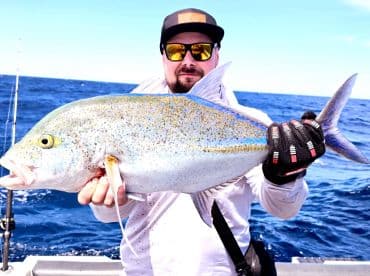 An angler proudly displays a large catch while fishing on the open ocean, showcasing the thrill of deep-sea fishing adventures.