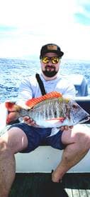A proud angler displays his impressive catch while fishing on the open ocean — a perfect moment for fishing enthusiasts.