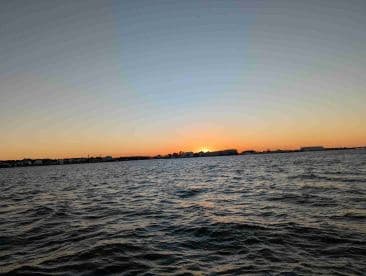 A stunning sunset over the coastline, capturing the serene beauty of the water and the horizon — perfect for romantic evenings or peaceful boat rides.