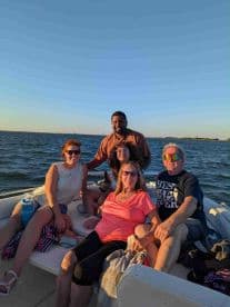 A cheerful group of friends enjoys a sunset outing on a boat, capturing the essence of fun and relaxation on the water.