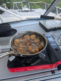 A portable gas stove is used to fry delicious food onboard, showcasing the culinary amenities available for a perfect day on the water.