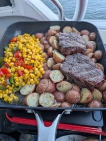 A delicious spread of grilled steak and vegetables served on a boat, showcasing the perfect amenities for a memorable dining experience on the water.
