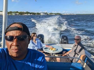 A group enjoys a leisurely boat ride with a meal on the table, capturing the essence of relaxation and fun on the water.