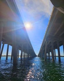 A view from underneath a bridge, capturing the sunlight and water reflections, but lacks clarity and focus.