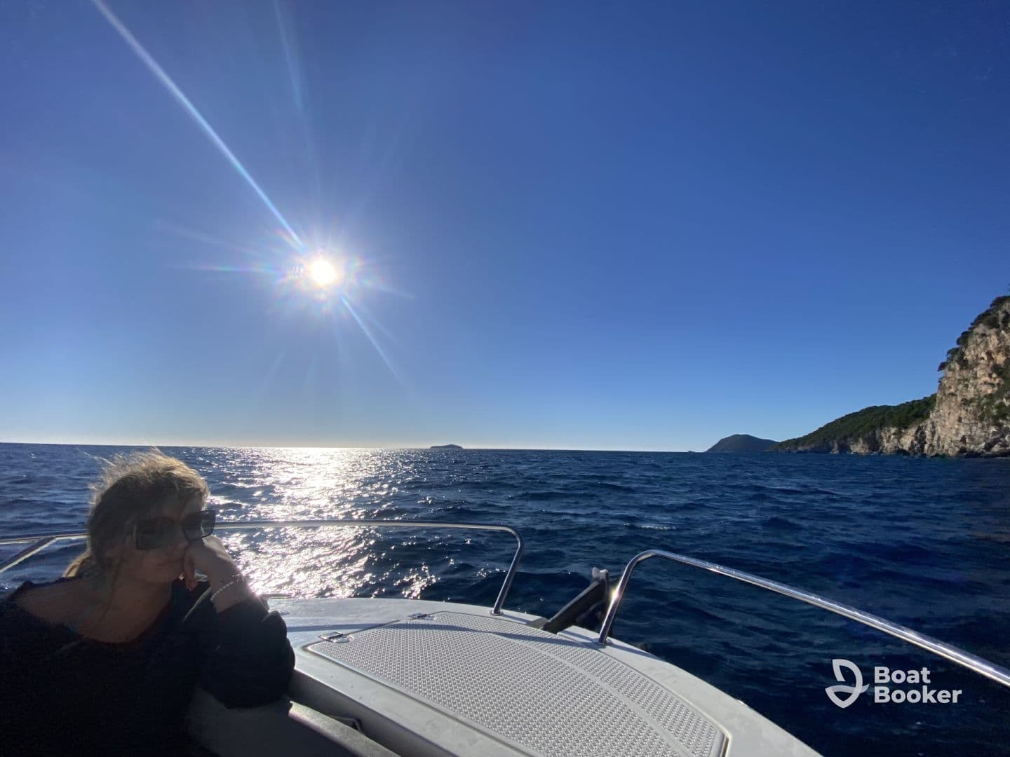 A woman enjoys the sunny ocean view while relaxing on a boat, capturing the essence of a serene day on the water.