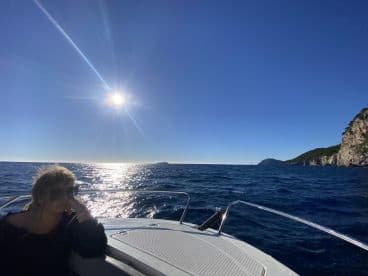 A woman enjoys the sunny ocean view while relaxing on a boat, capturing the essence of a serene day on the water.