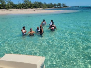 A lively group enjoys a refreshing swim in the crystal-clear waters at a sandbar, perfect for fun and relaxation under the sun.