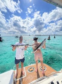 Two friends proudly display their fishing catch aboard a boat, showcasing a successful day on the water — perfect for fishing enthusiasts and adventure seekers.