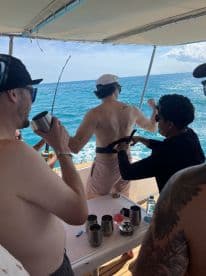 A lively group enjoys a fishing trip on a boat, with cocktails and camaraderie as they prepare for a fun day on the water.
