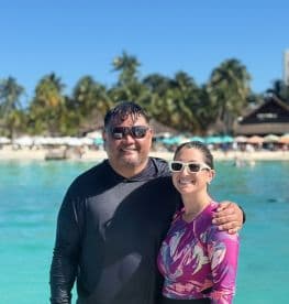 A joyful couple poses together in the clear waters of a tropical beach, perfect for memorable vacations and romantic getaways.
