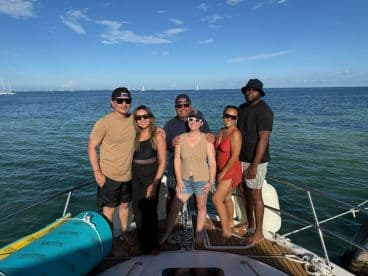 A cheerful group of friends poses together on the deck of a boat, enjoying a sunny day on the water — perfect for memorable outings and celebrations.