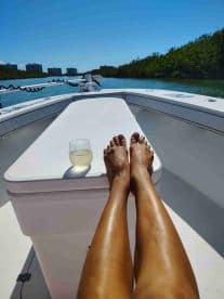 A relaxing moment on a boat with feet up and a drink in hand, showcasing the serene waterway and surrounding greenery — perfect for unwinding on a sunny day.