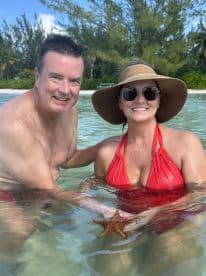 A couple enjoys a close encounter with a starfish while swimming in clear waters, showcasing a memorable wildlife experience in a tropical paradise.