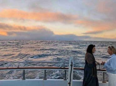 Two women enjoy a sunset on the deck of a boat, creating a perfect backdrop for memorable moments at sea.