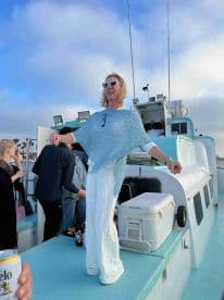 A joyful woman stands on the deck of a boat, celebrating with friends during a lively boat party — perfect for creating unforgettable memories on the water.