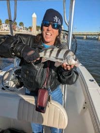 A proud angler shows off her catch aboard a boat, capturing the excitement of a successful fishing trip.