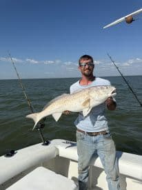 A proud angler holds up a large catch while fishing on a boat, showcasing the thrill of a successful day on the water.