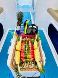 A beautifully arranged platter of fresh fruit and snorkeling gear onboard, perfect for a refreshing day on the water.