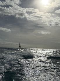 A scenic view of the ocean with a distant buoy and dramatic cloud cover, capturing the essence of a boating adventure.