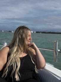A woman enjoys a moment of relaxation on a boat, gazing thoughtfully at the ocean — a perfect snapshot of leisure on the water.