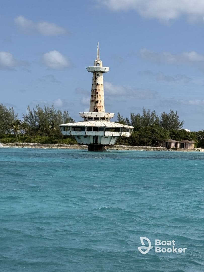 An abandoned structure rises above turquoise waters, surrounded by lush greenery, creating an intriguing yet unclear scene.