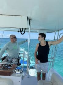 Two men enjoy a moment aboard a boat, with stunning ocean views in the background — a perfect snapshot of a day on the water.