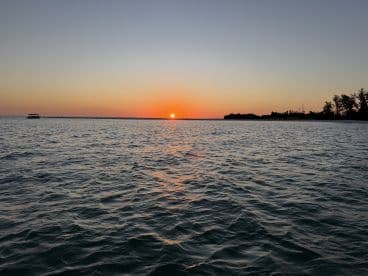 A serene sunset view over the water with a boat in the distance, creating a picturesque scene perfect for evening cruises.
