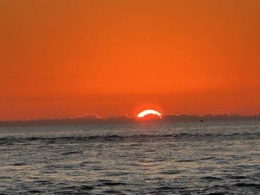 A breathtaking sunset over the ocean, casting vibrant orange hues across the sky — a perfect backdrop for evening boat cruises or romantic getaways.