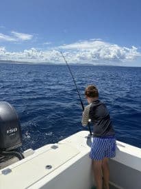 A child enjoys a fishing experience on a boat, casting a line into the deep blue ocean — a perfect moment for family adventures on the water.
