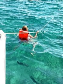 A child in a life jacket enjoys swimming in crystal-clear waters, showcasing a fun snorkeling experience perfect for family adventures.