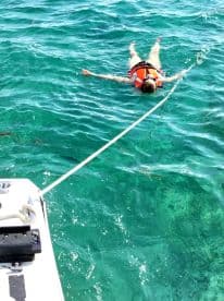A person enjoys a refreshing swim in crystal-clear waters while wearing a life jacket, showcasing the fun and safety of water activities.