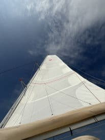 A stunning view of a sailboat's sail against a backdrop of blue skies, showcasing the beauty of sailing adventures on the open water.