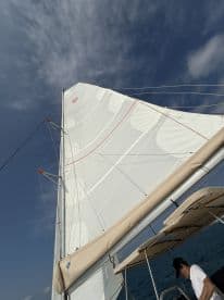 A close-up view of a sailboat's sail against a backdrop of blue skies, showcasing the beauty of sailing on open waters.