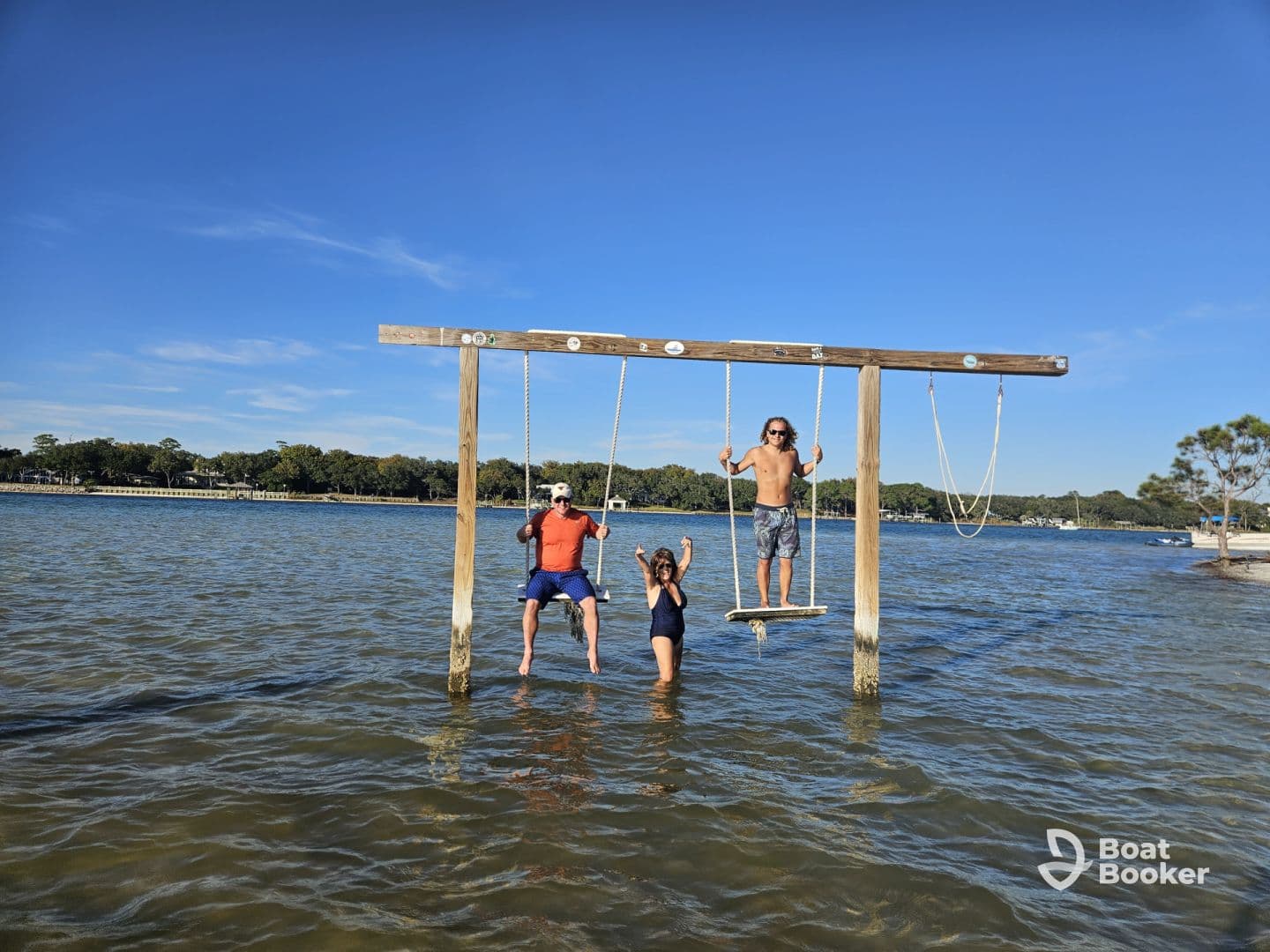 A fun-filled moment with friends enjoying a swing in shallow water, capturing the essence of summer adventures by the lake.