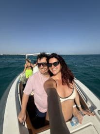 A cheerful couple takes a selfie on a boat, enjoying a sunny day on the ocean — perfect for capturing memorable moments during a fun outing.