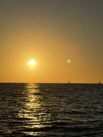 A breathtaking sunset over the ocean, with gentle waves reflecting the golden light — a perfect backdrop for sailing adventures.