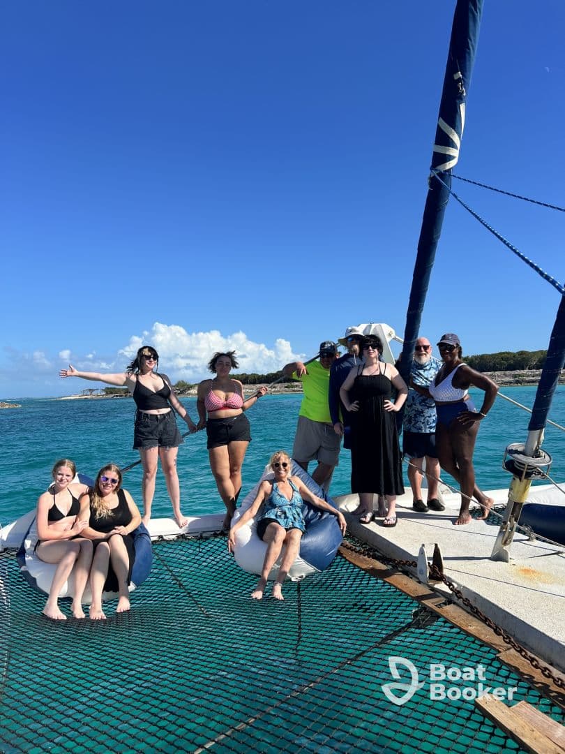 A lively group enjoys a day on a catamaran, soaking up the sun and celebrating together in the beautiful turquoise waters.